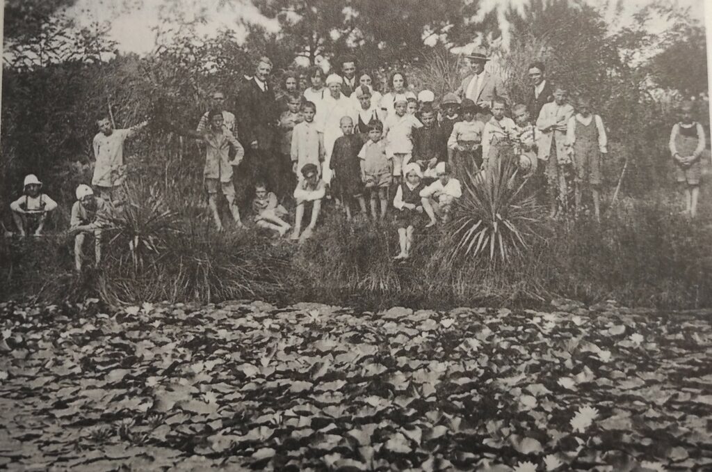 Vittorio Belli (in abito scuro) con un gruppo di bambini presso il laghetto delle ninfee nella pineta di Igea Marina -Collezione privata Bruno Belli